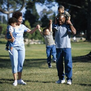 two parents, each holding a child and swinging a third child in the middle